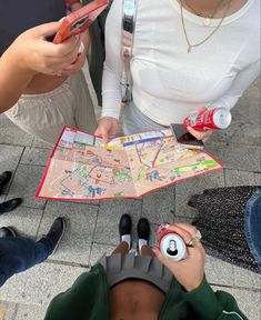 three people looking at a map on the ground while one person holds a cell phone