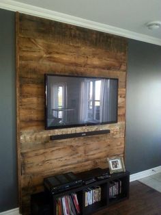 a flat screen tv mounted to the side of a wooden wall in a living room