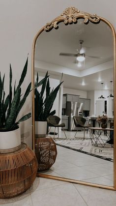 a large mirror sitting on top of a floor next to a potted plant in front of a dining room table