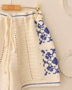 a white crocheted skirt hanging on a clothes line with a wooden hanger