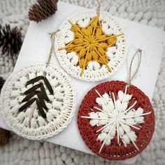 three crocheted christmas ornaments with pine cones on the top one is red, white and yellow