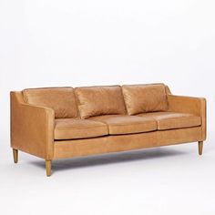 a tan leather couch with three pillows on it's back and two armrests