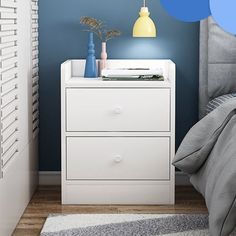 a white night stand with two drawers and a lamp on the nightstand next to it