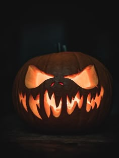 a carved pumpkin with an evil face on it's side and teeth in the middle