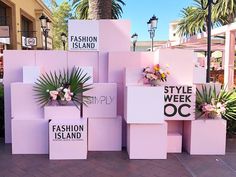 several pink boxes with flowers and palm trees in the background