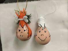 two eggs with faces painted on them are hanging from a string and decorated with carrots