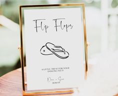 a sign that says flip flops on it sitting on top of a wooden table