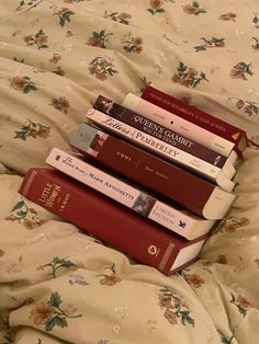 a stack of books sitting on top of a bed next to each other in front of a pillow