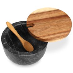 two wooden spoons are in a black bowl with a wood lid on the side