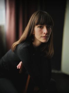 a woman sitting in a chair with her hands on her hips and looking at the camera