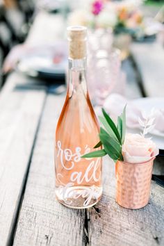 a bottle of wine sitting on top of a wooden table next to a flower vase