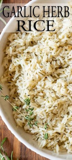 garlic herb rice in a white bowl on a wooden table with herbs around it and text overlay that reads garlic herb rice