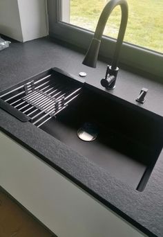 a black sink sitting on top of a counter next to a window