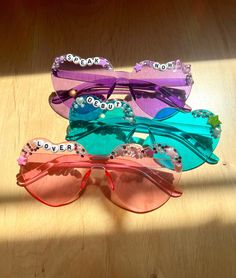 three pairs of colorful sunglasses sitting on top of a wooden table next to each other