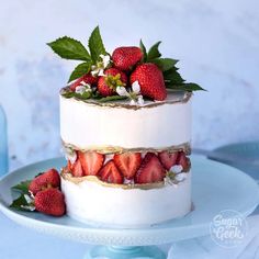 a three tiered cake with strawberries on top and flowers in the middle, sitting on a blue plate