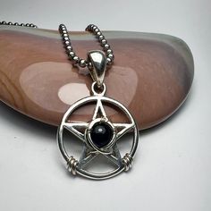 PENTACLE, Black Onyx,, Pentagram, Sterling Silver, Magic, Model  Bruce designed this sterling silver pentacle to last a lifetime. I designed it in the 1980s. I sent the design to my friend Vicki  in Thailand. She made a cast of my design and cast it into silver. this particular pendant was cast in Thailand. I soldered on the bail and my daughter, Jamie, set the stone with sterling silver wire. . The size is about 7/8"(22MM) tall, not including the bail. The pendant has a mirror finish on both sides. It is smooth and gentle to the touch. I am including a stainless steel chain. Please select your preferred length. The pentacle is an ancient revered symbol. It represents the four elements (fire, water, air, earth) and spirit. The circle represents the universe. Thank you for considering our w Pagan Pentagram, Pentagram Jewelry, Pentacle Necklace, Wicca Jewelry, Black Onyx Pendant, Onyx Pendant, Fire Water, Necklace Sterling Silver, Steel Chain