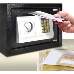 a hand holding a credit card in front of a safe