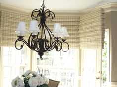 a chandelier hanging from the ceiling in a dining room with white flowers on it