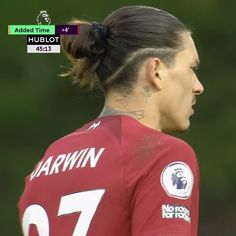 a female soccer player with her hair in a ponytail wearing a red jersey and tattoos