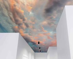 an empty room with clouds painted on the ceiling and lights in the hallway leading up to it