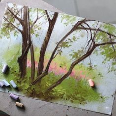 some crayons are laying on top of a piece of paper with trees in the background