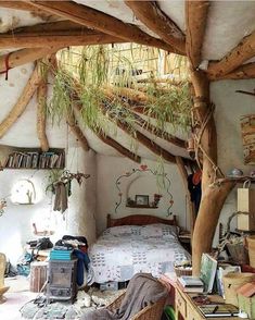 a bed sitting under a wooden roof next to a table and books on top of a book shelf