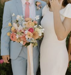 a bride and groom standing next to each other in front of trees with flowers on their wedding day