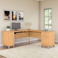 an office desk with a computer on it in front of a window and pictures hanging on the wall