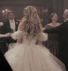 a woman in a wedding dress is dancing with other people