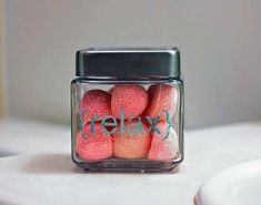 a glass jar filled with pink and green colored candies sitting on top of a white table