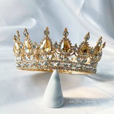 a gold tiara is sitting on top of a white cone shaped object, which sits on a white cloth