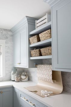 a kitchen with white cabinets and baskets on the shelf above the countertop, along with other items