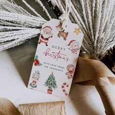 a christmas gift tag sitting on top of a table next to pine cones and twine