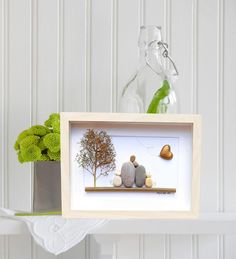 two rocks sitting on top of a shelf next to a vase with a tree in it