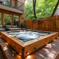 a hot tub sitting on top of a wooden deck next to a patio with furniture