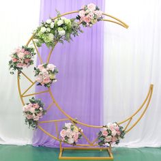 a flower arrangement on a stand in front of a purple curtain with white and pink flowers