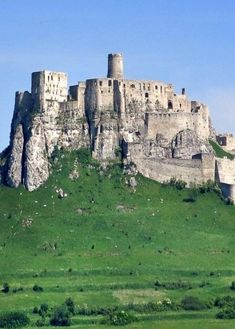 an old castle sitting on top of a green hill