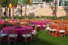 tables and chairs are set up on the grass for an event with bright colored linens