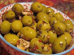 a bowl filled with green olives on top of a table