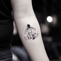 a woman's arm with a tattoo on it that has an image of winnie the pooh