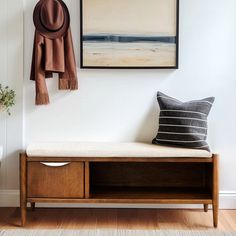 a wooden bench sitting next to a wall with a hat hanging on it's side