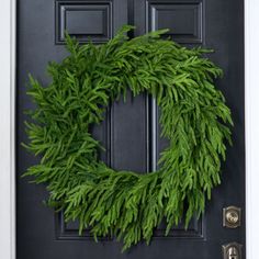 a black door with a green wreath on it