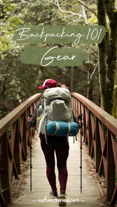 a woman walking across a wooden bridge in the woods with backpacks on her back