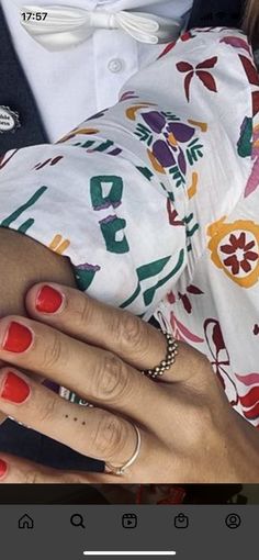 a woman's hand with two rings on it and another person wearing a white shirt