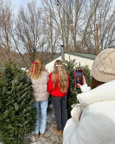 three girls looking at christmas trees in the snow