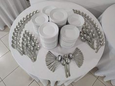 a table topped with lots of white plates and silverware