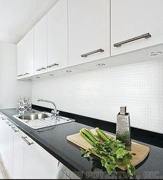 a kitchen with white cabinets and black counter tops, along with a bamboo painting on the wall