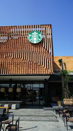 a starbucks coffee shop with wooden slats on the roof and tables in front of it