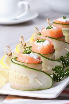 cucumber and smoked salmon appetizers on a white plate with lemon wedges