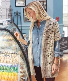 a woman standing next to a display case filled with colorful candies and other sweets